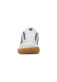 Baskets blanches et noires avec une semelle en caoutchouc naturel, fermeture à lacets à l'avant et accents en daim. Présente un logo sur la languette et un design rayé sur le côté.