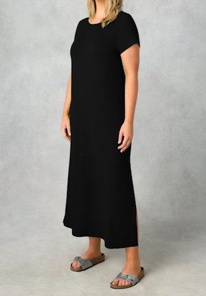 Czarna długa sukienka z krótkimi rękawami, gładka tkanina i boczne rozcięcia. W zestawieniu z szarymi klapkami na jasnoszarym tle.