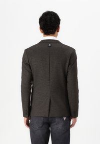 Donkergrijze blazer met een gladde textuur, gestructureerd ontwerp en ingesneden revers. Voorzien van een klein logo detail aan de achterkant.