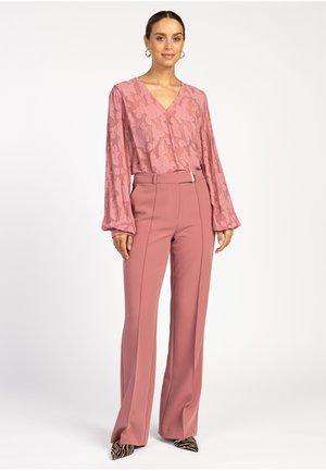 Roze blouse met een patroon, een V-hals en lange mouwen, gecombineerd met hoge taille, ruime broeken in een bijpassende roze tint.