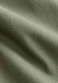 Tissu vert olive avec une surface lisse et texturée ; présente un léger nervuré et un subtil éclat, indiquant un textile durable et polyvalent.