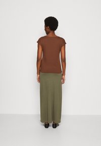 Brown short-sleeve top paired with a long, olive green skirt. Features a simple design with a soft texture and a relaxed fit.