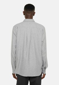 Grå flanellsskjorta med långa ärmar, knappmanschetter och en bakfåll. Mjuk textur, normal passform, standardkrage och inga synliga mönster.