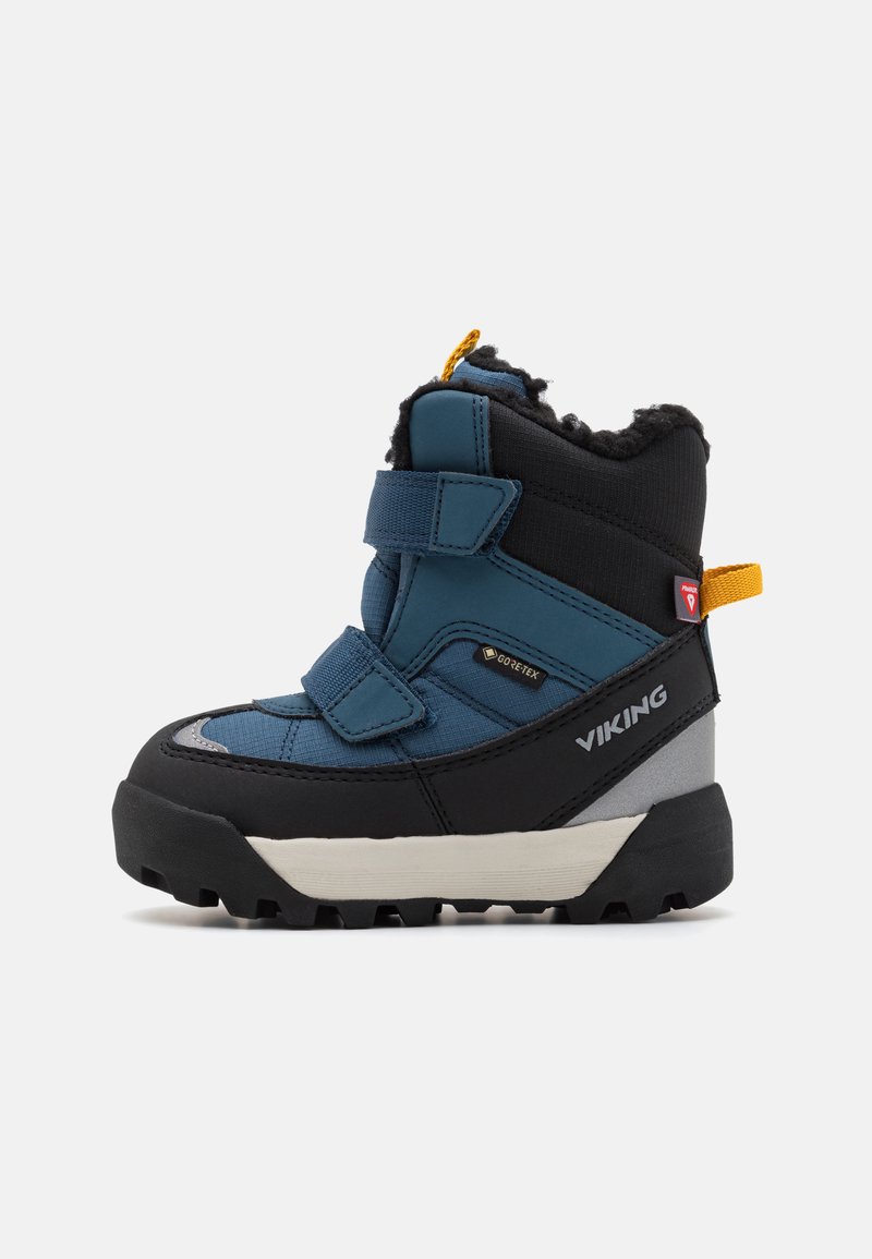 Zili un melni ziemas zābaki ar mākslīgās kažokādas oderi, Velcro siksnām, gumijas zoli un GTX zīmolu. Ievērojama pazīme ir izteikta dzeltena cilpa.