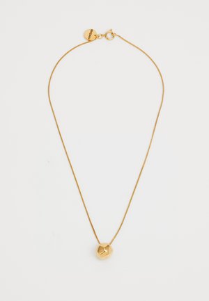 Zlatni ogrlica s tankim lancem i geometrijskim privjeskom koji ima polirani, zaobljeni oblik i detalj u obliku srca.