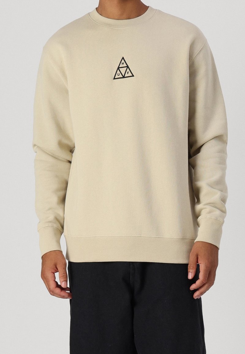 Felpa beige in misto cotone con scollo rotondo, maniche lunghe e un piccolo logo triangolare nero sul petto.