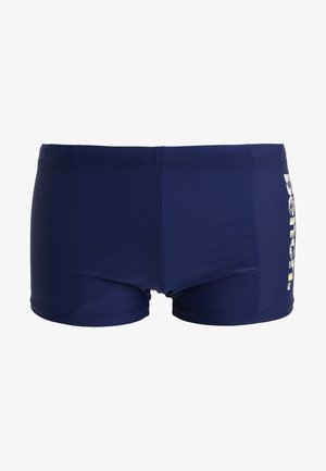Navy blue swim shorts made of stretchy fabric. Features a fitted design with a logo print on the side and an elastic waistband.