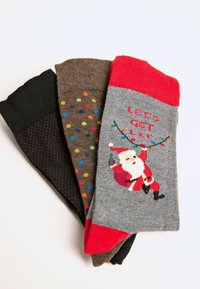 Three pairs of socks: black with red dots, brown with colorful polka dots, gray with Santa graphic and red cuff, all in soft knit material.