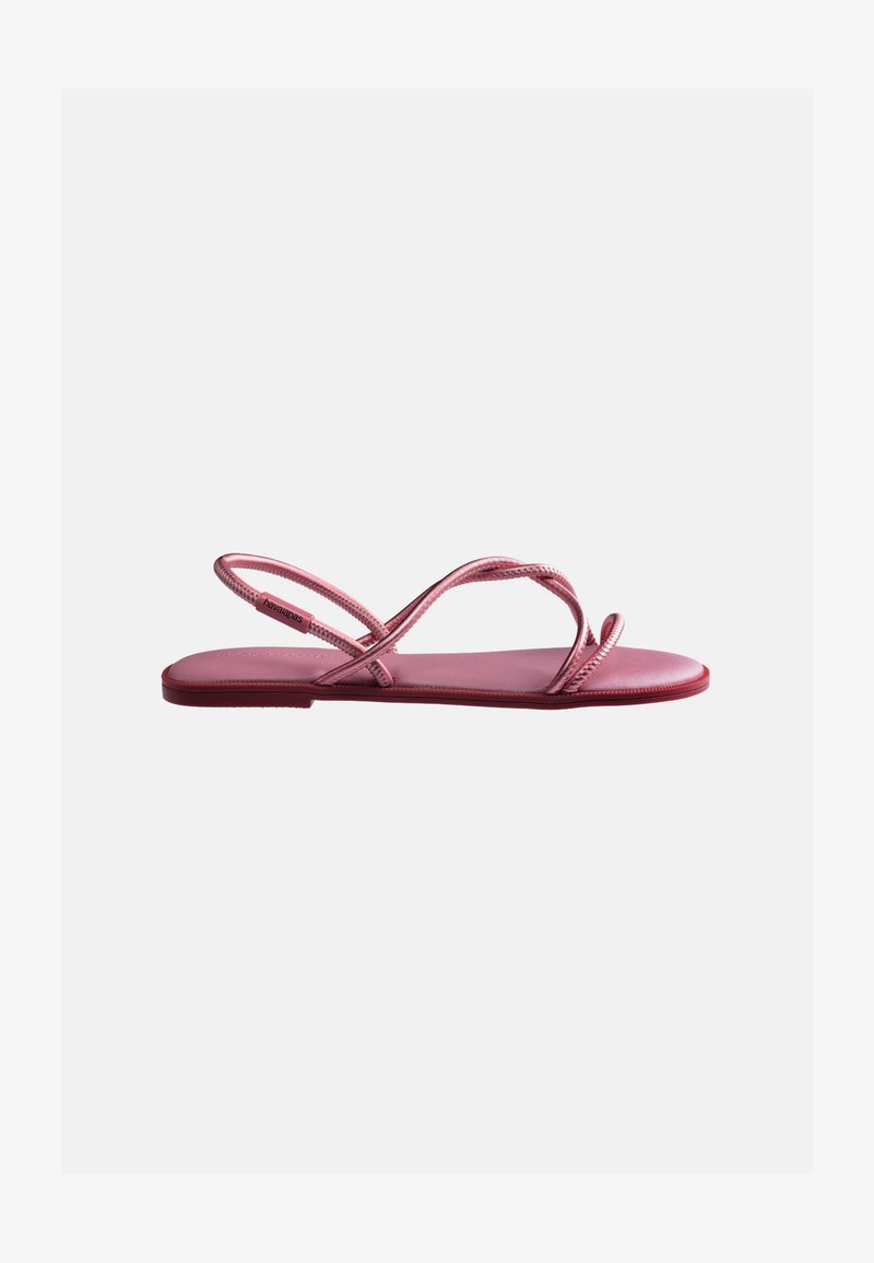 Sandale plate rose avec des fines brides croisées et un arrière en lanière, semelle minimaliste, conçue pour un usage décontracté.