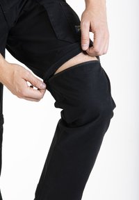 Pantalons cargo noirs avec ouvertures latérales zippées, fabriqués en tissu durable, dotés de poches et d'une coupe épurée pour plus de polyvalence.