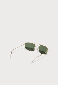 Gafas de sol metálicas doradas con lentes verdes, forma rectangular, montura delgada y puntas de las patillas transparentes. Cuenta con un diseño de doble puente.