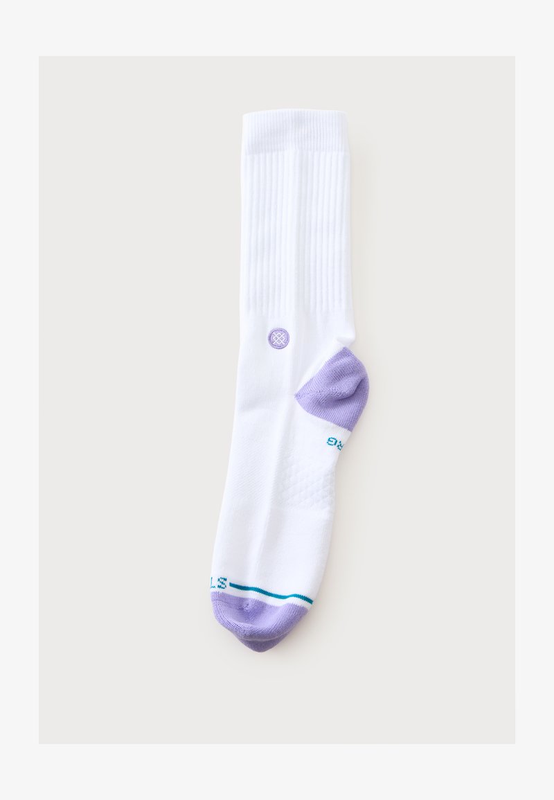Chaussette blanche montante avec bord-côte, talon et pointe violets, bande turquoise à la pointe et petit logo circulaire violet près de la cheville.
