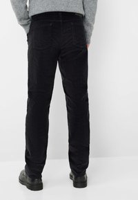 Zwarte corduroy broek met een rechte pijpdesign, voorzien van twee achterzakken en een gestructureerde stof die diepte aan het oppervlak toevoegt.