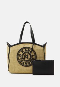 Sac en paille tressée jaune avec logo noir, doté d'un contour et de poignées en synthétique noir. Comprend une petite pochette zippée noire.