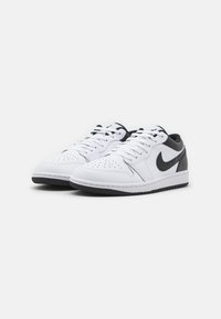 Białe sneakersy na sznurówki z czarnymi akcentami, górna część z gładkiej skóry, perforowany przód, gumowa podeszwa i klasyczne elementy wzornictwa Air Jordan.
