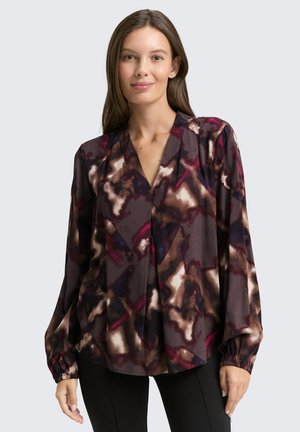 Blusa a maniche lunghe in un marrone scuro con un motivo astratto in crema, viola e marrone. Presenta un colletto a V e polsini arricciati. Tessuto morbido.