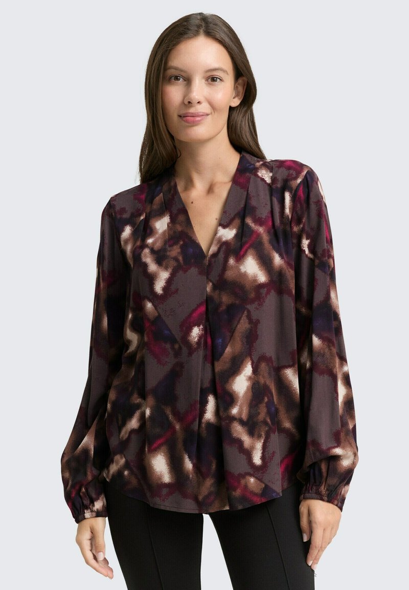 Long-sleeve blouse in dark maroon with an abstract pattern of cream, purple, and brown. Features a V-neck and gathered cuffs. Soft fabric.