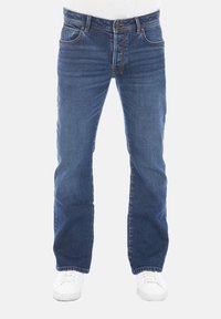 Jeans de mezclilla azul con un corte recto, cinco bolsillos y detalles de costura claros. Llevados con zapatillas blancas.