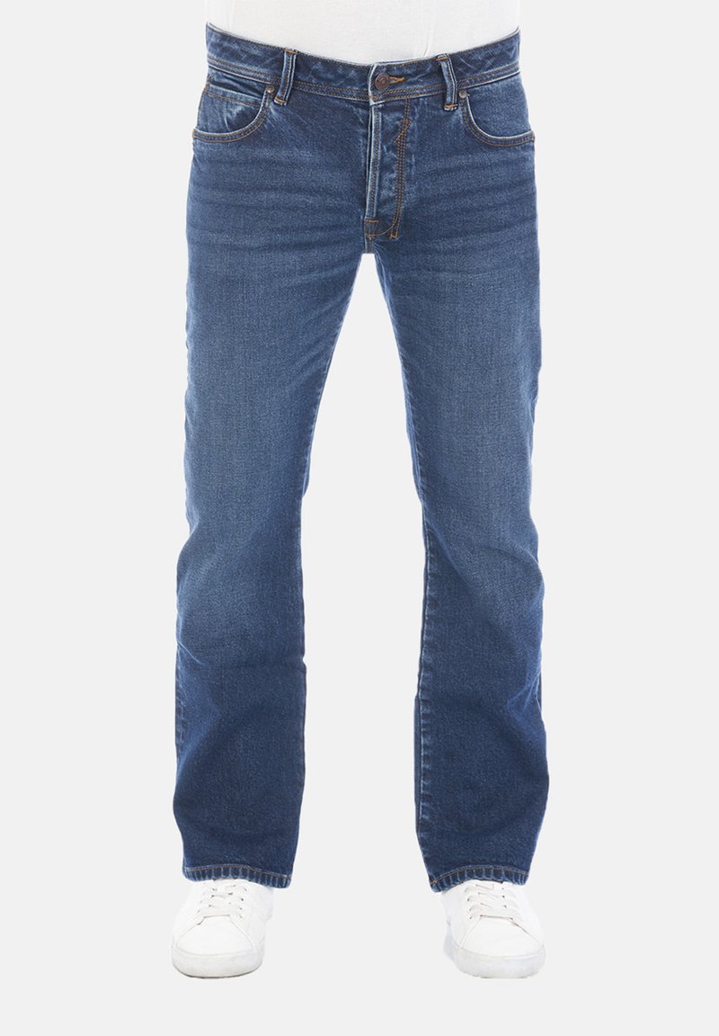 Jeans de mezclilla azul con un corte recto, cinco bolsillos y detalles de costura claros. Llevados con zapatillas blancas.