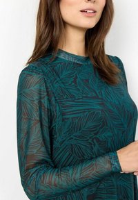 Top de manga larga en verde azulado con un patrón de hojas, fabricado en tejido transparente, con un cuello redondo y puños ajustados.