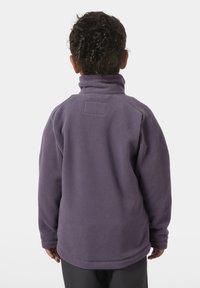 Fialová fleecová bunda s vysokým límcem, texturovaným povrchem a malou nášivkou na zadní straně. Rukávy jsou mírně volné, lem je zaoblený.