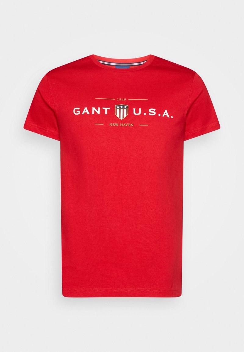 T-shirt en coton rouge à manches courtes et col rond. Sur le devant, on trouve un texte blanc : "GANT U.S.A." et "NEW HAVEN" avec un petit logo en forme de bouclier.
