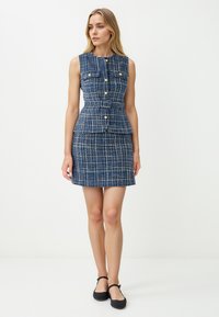 Abito in tweed blu con vita a peplum aderente, bottoni dorati e design senza maniche. Presenta una gonna corta e un sottile motivo a quadretti.