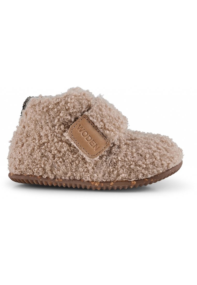 Stivale beige per bambino realizzato in tessuto morbido, con cinturino in velcro e suola in gomma con motivo testurizzato. Logo "WODEN" impresso sul cinturino.