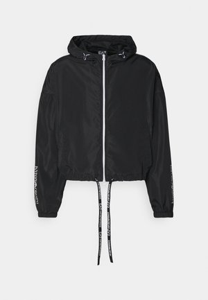 Fekete rövidített dzseki kapucnival, elől cipzárral, elasztikus mandzsettákkal és húzózsinórral. Fehér logóval a ujjakon és az alján.