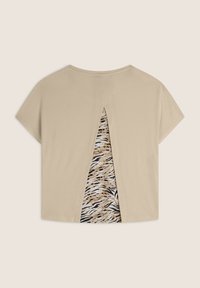 T-shirt beige con maniche corte, caratterizzata da un'apertura a forma di chiave sulla schiena che rivela uno strato interno a motivo con stampa animale.