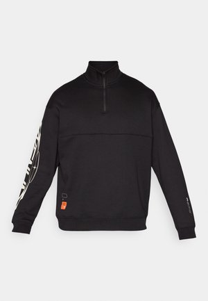 Black pullover sweatshirt with a high collar, half-zip, and long sleeves. Features textured paneling and white graphic designs on the sleeve.