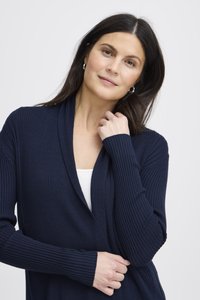 Meresinine soonikkoes kardigan, millel on salli kaelus ja pikad varrukad. Valmistatud tekstuurse kangaga, iseloomustab seda lõdvestunud lõige ja sile ning pehme pind.