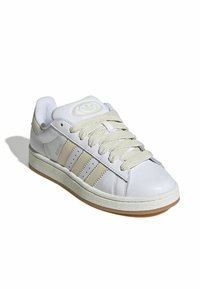White leather sneaker with beige accents, featuring round toe, flat laces, three stripe design, and textured rubber sole.