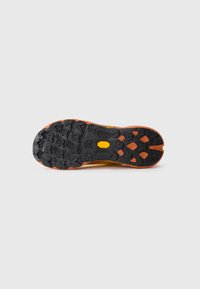 Semelle de chaussure de trail avec des crampons multidirectionnels noirs et orange profonds pour une adhérence améliorée, comportant un logo Vibram jaune central.