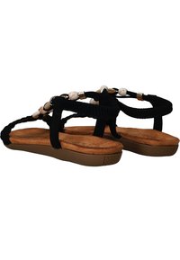 Sandales en daim noir avec un design de lanières tressées et des perles décoratives. Semelle rembourrée marron avec grip texturé. Vue de côté.