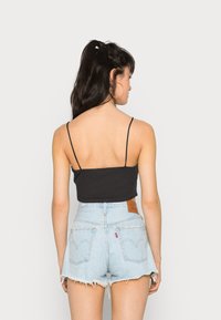 Top cropped preto com alças finas, combinado com calções de ganga azul claro de cintura alta, com bainha desfiada e bolsos traseiros.
