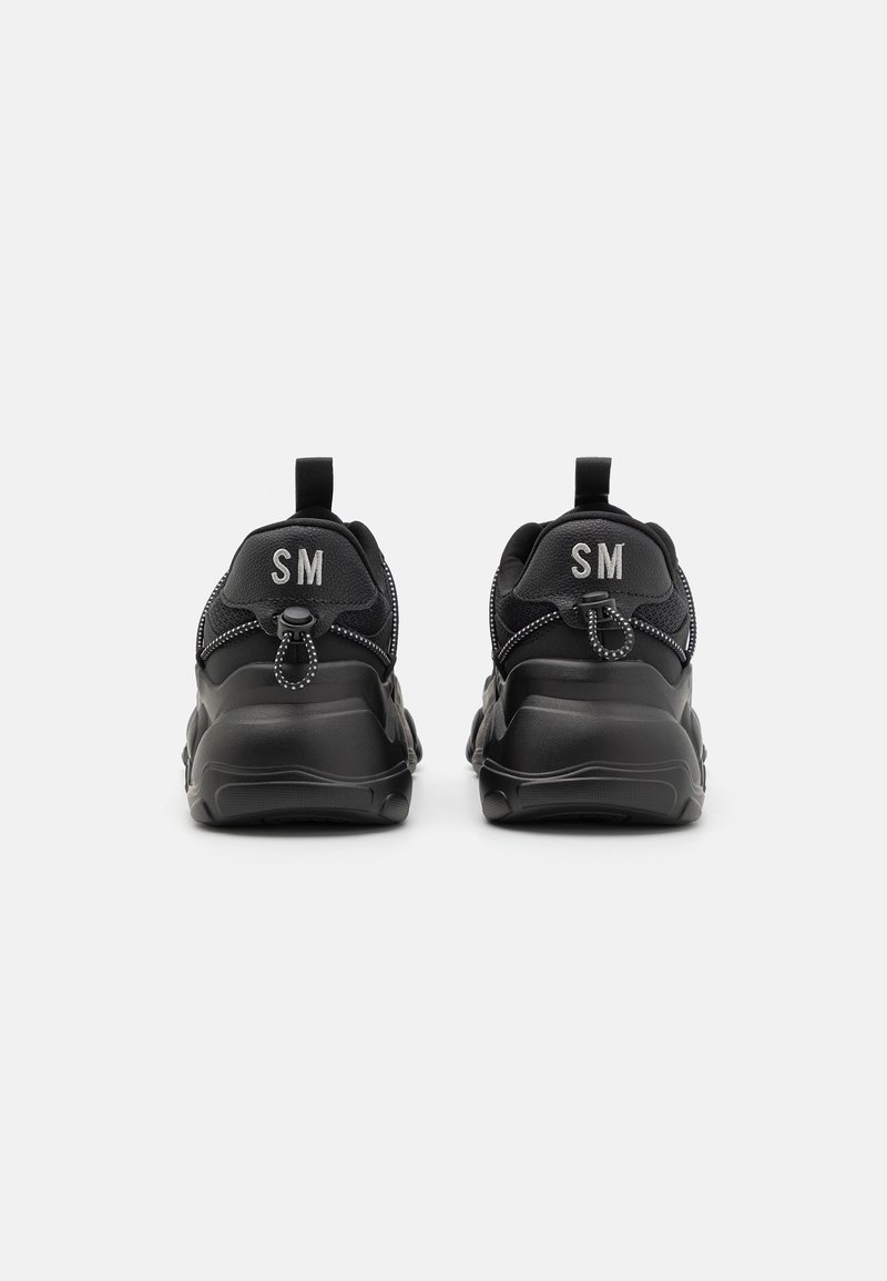 Sneaker sportive nere con tomaia testurizzata, cuciture a contrasto e linguette, con "SM" ricamato sul retro.