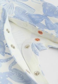 Blau-weißes Stoff mit Blumenmuster und metallischen Druckknöpfen, mit glatter Textur und einem weichen, leichten Gefühl.