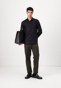 Black button-up shirt, olive green pants, black leather shoes, and a black tote bag. Simple design with sleek textures and straight lines.