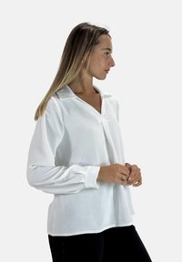 Witte blouse met lange mouwen en kraag, met een ontspannen pasvorm, textuurstof en een plooidetail aan de voorkant voor een vloeiende silhouet.