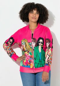 Lys pink zip-op jakke med farverige illustrerede kvinder på ærmerne. Fremstillet af blødt stof med ribbede manchetter og talje.