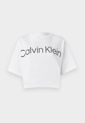 Hvit cropped t-skjorte laget av bomull, med rund hals og korte ermer. "Calvin Klein" er trykket i fete svarte bokstaver over fronten.
