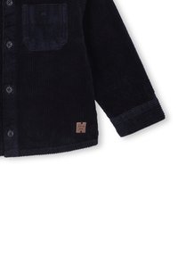 Marineblauwe corduroy shirt met een voorzak, knoopsluiting, textuurstof en een leren label met merk bij de zoom.