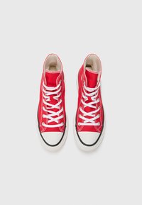 Höga sneakers i röd kanvas med vita snören, en vit gummikappa vid tåspetsen och en svart gummisula. Inga synliga mönster eller accenter.