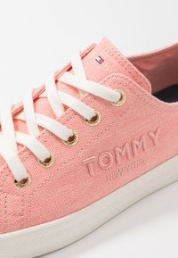 Rosa Stoff-Sneaker mit weißen Schnürsenkeln, goldenen Ösen und strukturiertem weißen Sohlenabsatz. Besticktes "TOMMY NEW YORK"-Detail an der Seite.