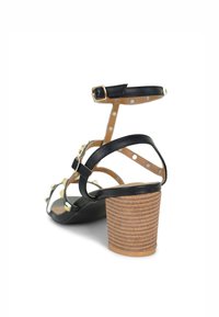 Zwarte sandalen met bandjes, voorzien van een blokhak en gouden accenten, met een gestructureerde bruine hak en een stippenpatroon op de binnenste bandjes.