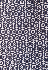 Tessuto blu navy e bianco con un motivo geometrico di esagoni e ovali intrecciati, caratterizzato da una struttura tessuta e testurizzata.