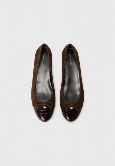 Ballerines en daim marron avec un embout en cuir de crocodile glacé marron foncé, dotées d'un nœud décoratif et d'un petit logo métallique.
