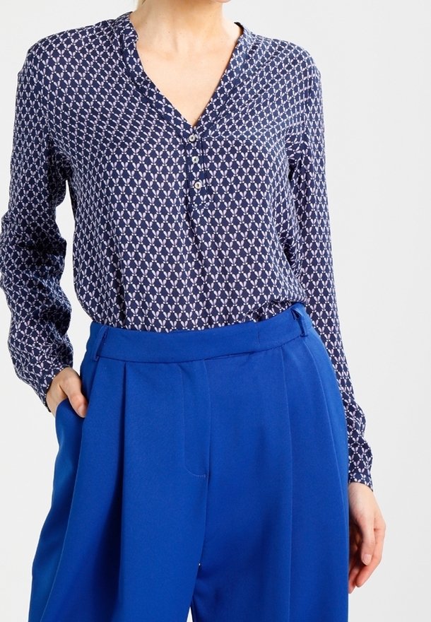 Blusa a fantasia navale con scollo a V abbottonato, maniche lunghe e design geometrico in rilievo abbinata a pantaloni a vita alta blu brillante.