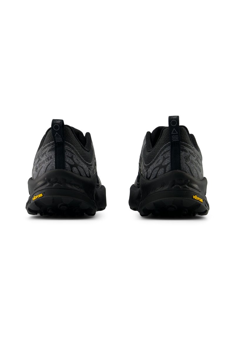 Baskets de sport noires avec un dessus texturé, un talon renforcé et une semelle Vibram. Conception légère avec des languettes pour un enfilage facile.